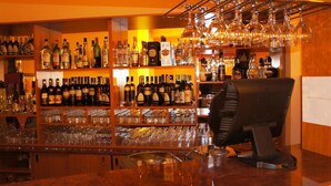 Uma área de bar com estantes de garrafas de bebidas e copos.