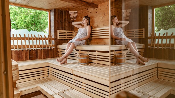 A wooden sauna with tiered seating and a large window. - Panoramahotel Gürtl (Haus)