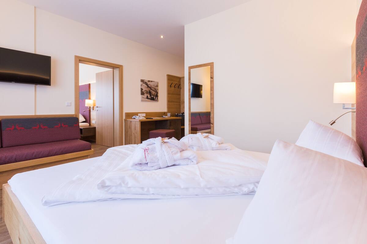 A hotel room with a bed, a sofa, a desk, and a TV.