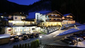 A multi-story hotel with a ski lift, snow-covered surroundings, and a parking area. - Panoramahotel Gürtl (Haus)