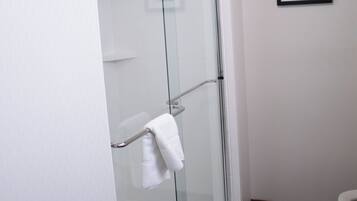 A bathroom with a glass-enclosed shower, a white toilet, and a framed picture on the wall.
