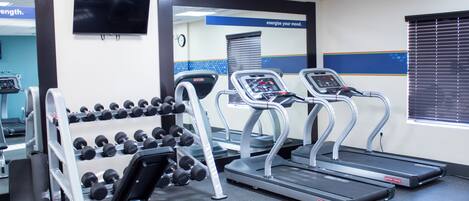 Una palestra con tapis roulant, manubri e una TV appesa al muro.