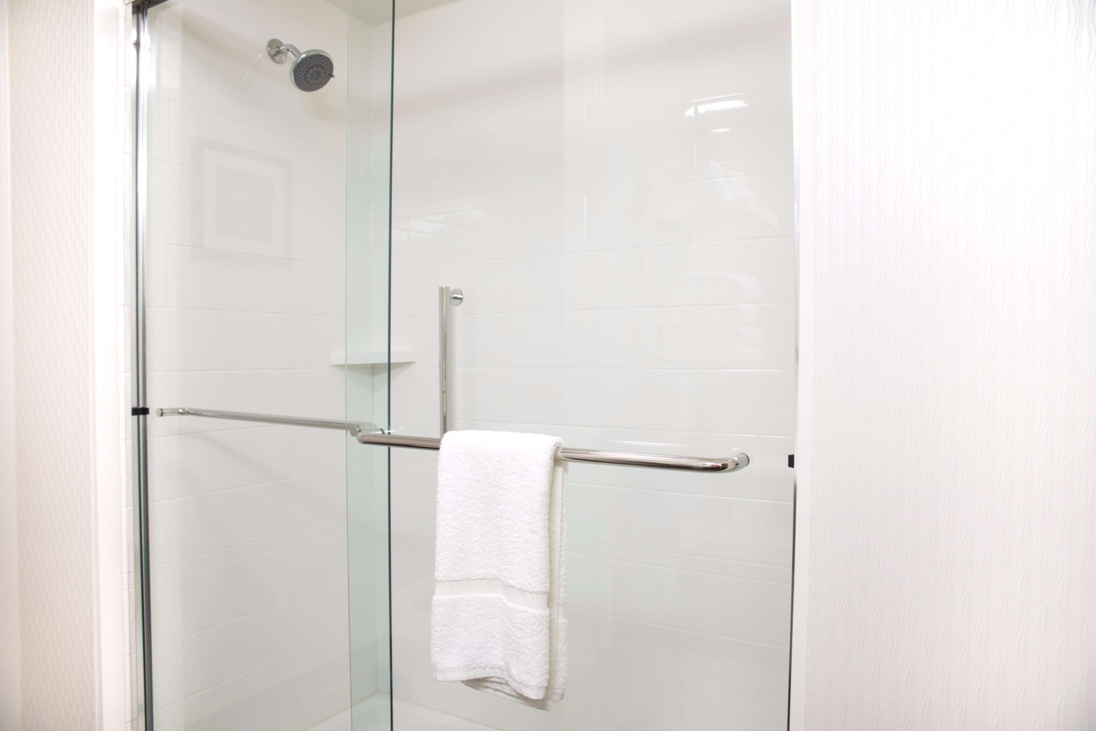 A glass-enclosed shower with a white towel on a metal towel bar.