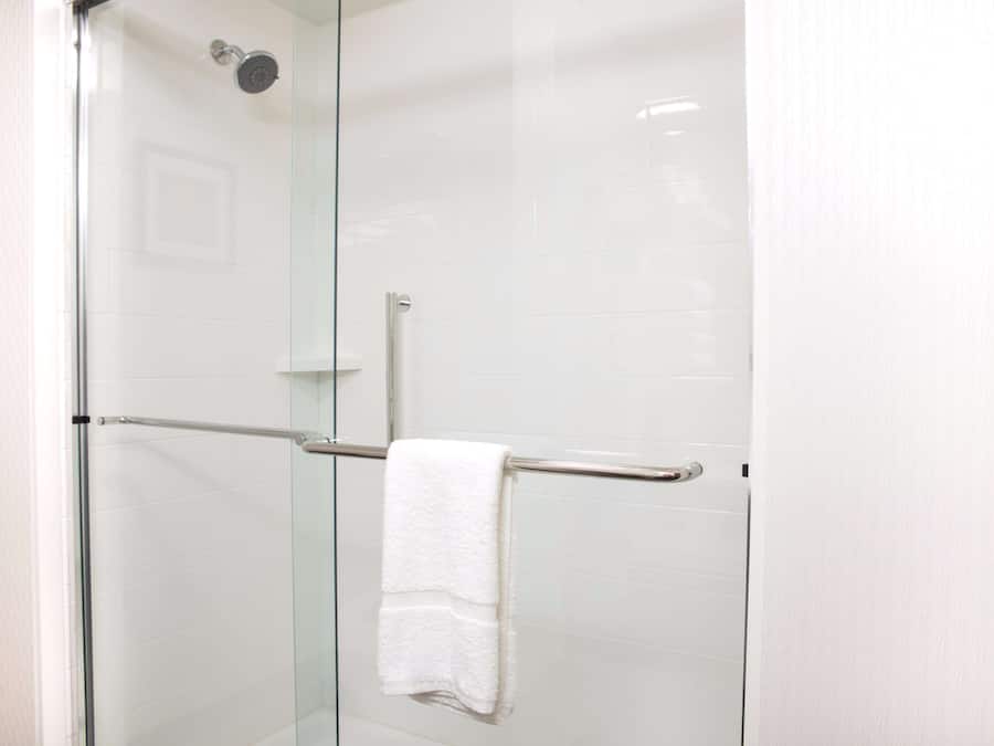 A glass-enclosed shower with a white towel on a metal towel bar.