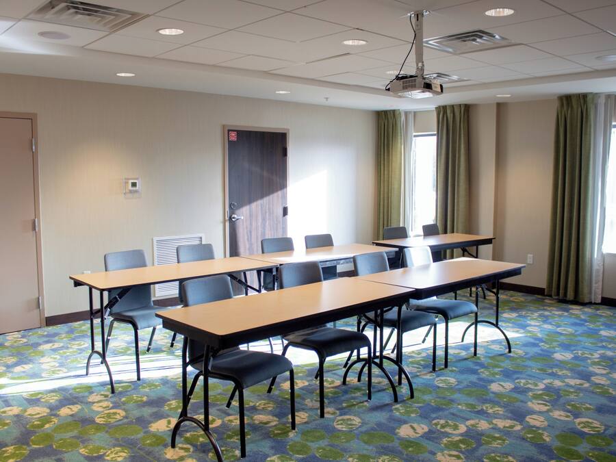 A conference room with a long table, chairs, and a projector.