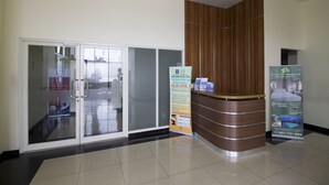 A reception area with a glass door entrance, a wooden reception desk, and a poster advertising services and facilities.