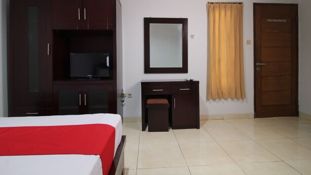 Ein Hotelzimmer mit Bett, Schreibtisch, Fernseher, Spiegel und Tür.