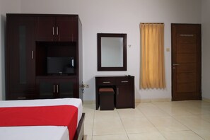 Une chambre d’hôtel avec un lit, un bureau, une télévision, un miroir et une porte.