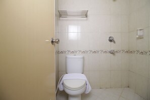 A bathroom with a toilet, a shower, and a towel rack.