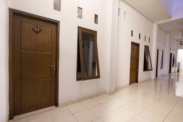 A hallway with a wooden door marked '11', a mirror, and a tiled floor. - RedDoorz @ Seturan Raya (Depok)