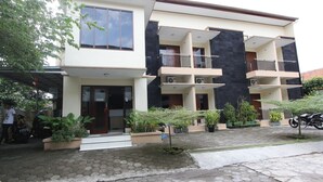 A modern two-story building with multiple balconies, a covered entrance, and potted plants. - RedDoorz @ Turangga Sari (Depok)