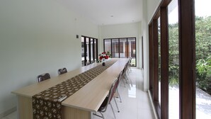 A conference room with a long table, chairs, and a window with a view of greenery. - RedDoorz @ Turangga Sari (Depok)