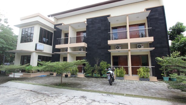 A modern two-story building with balconies, a paved driveway, and potted plants. - RedDoorz @ Turangga Sari (Depok)