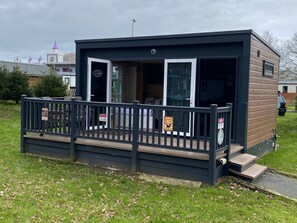 A small, modern cabin-style building with a deck and a sliding glass door entrance. - Gulliver's Hotel (Warrington)