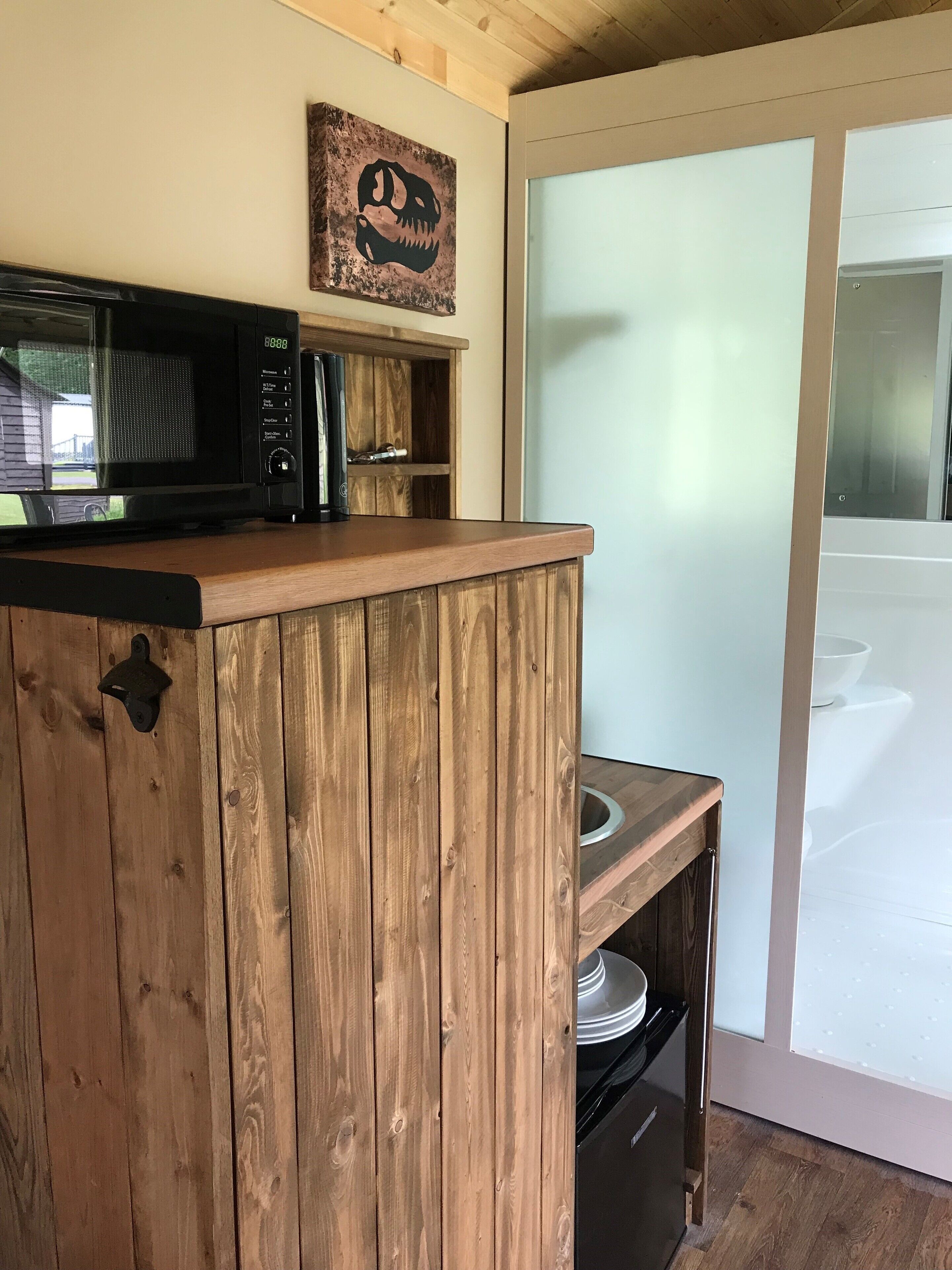 A kitchen with a wooden counter, a microwave, and a rustic wall decoration.