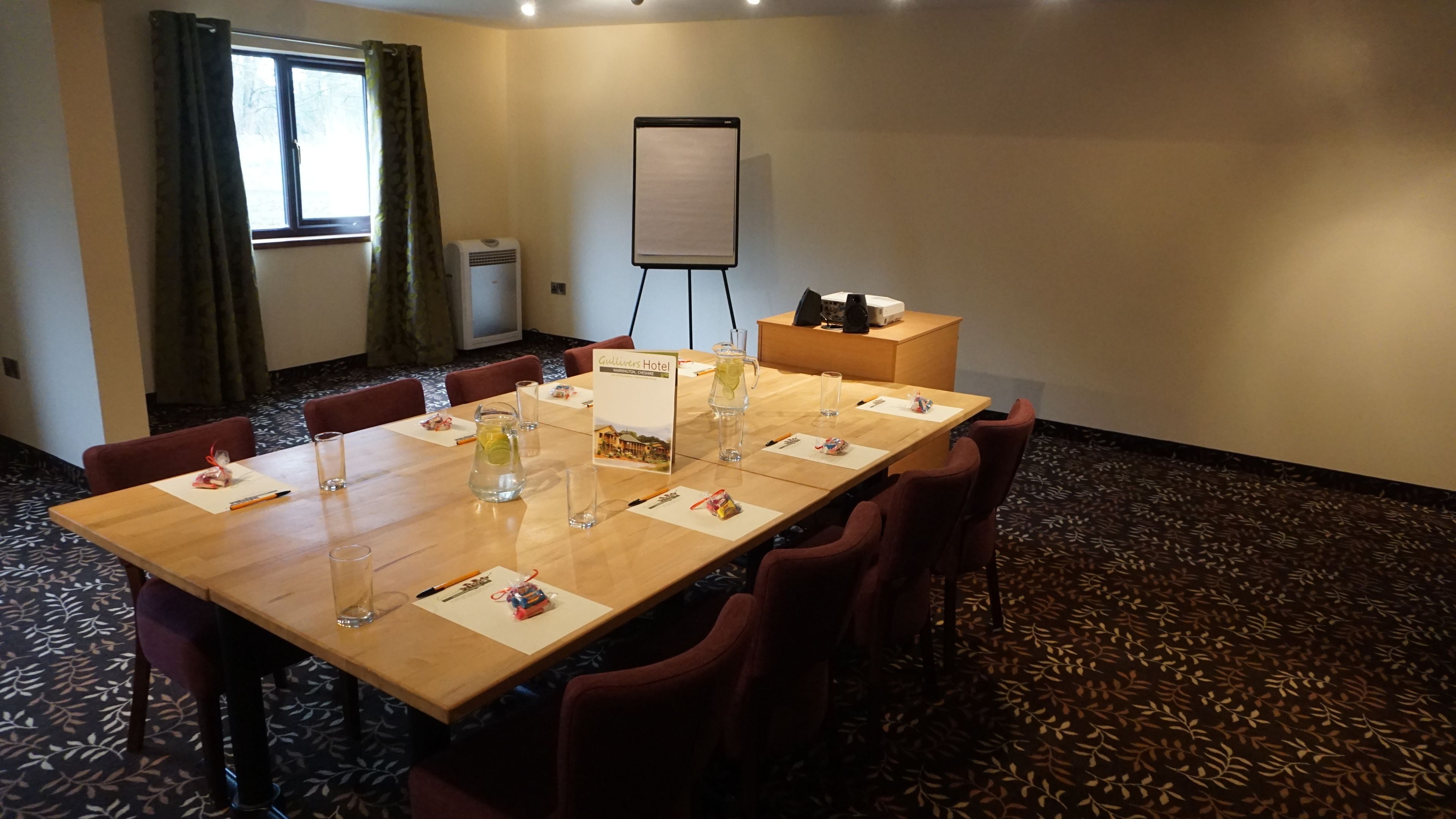 A conference room with a long table, chairs, a whiteboard, and a projector.