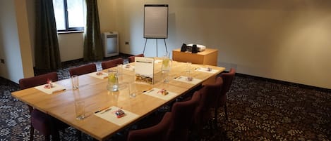 A conference room with a long table, chairs, a whiteboard, and a projector.