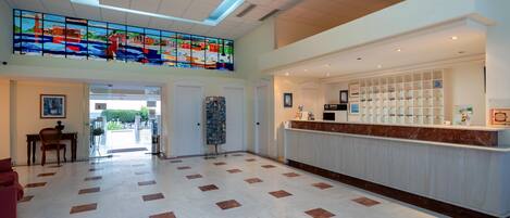 A spacious lobby with a high ceiling, a reception desk, and a large stained glass window.