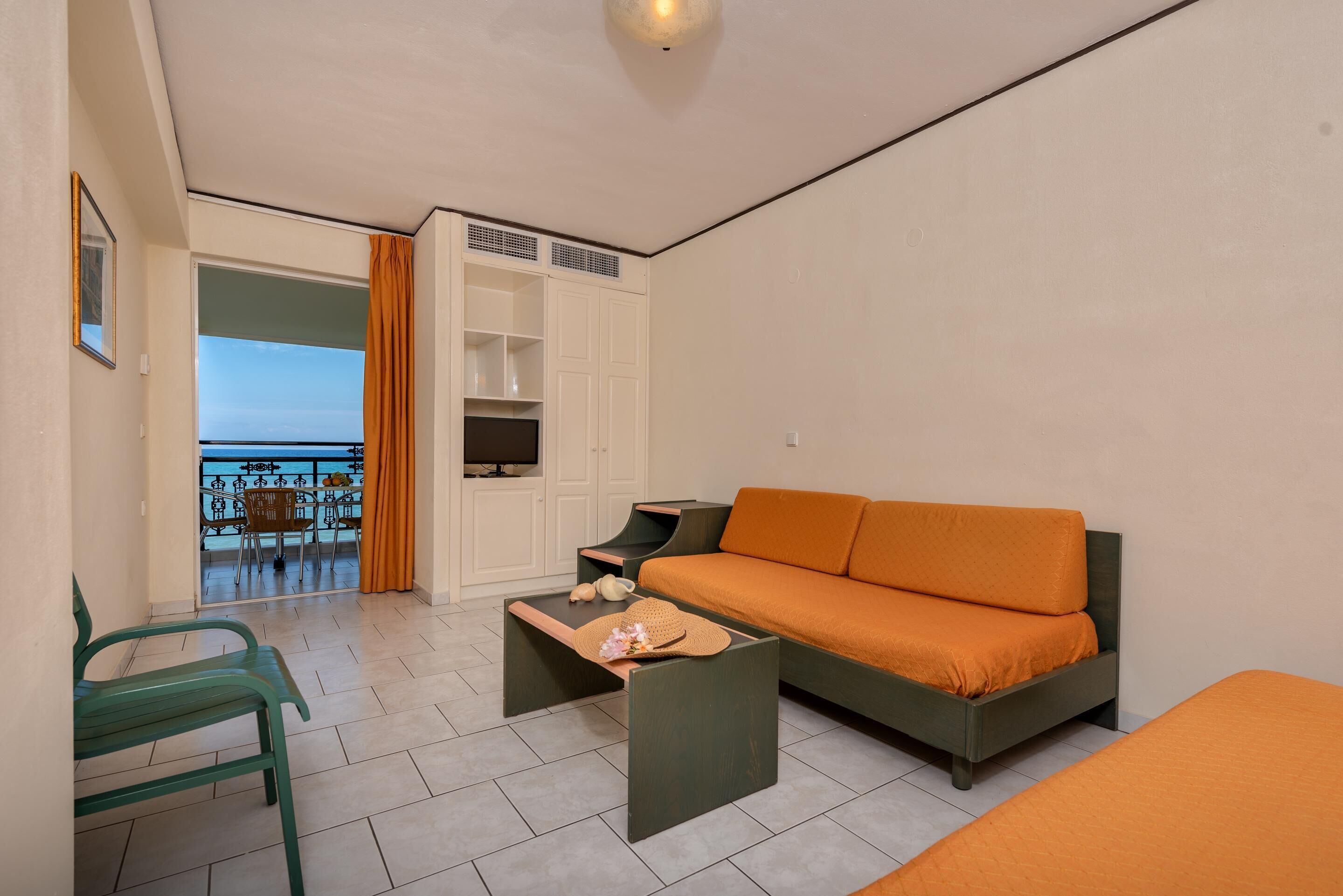 Una habitación de hotel moderna con sofá, una mesita, una silla y un balcón con vistas.
