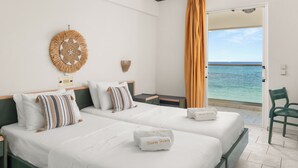 A hotel room with two beds, a view of the sea, and a beach chair. - Porto Iliessa by GHH (Zakynthos)