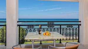 A balcony with a table set for two, featuring a bottle and glasses, and a fruit basket. - Porto Iliessa by GHH (Zakynthos)