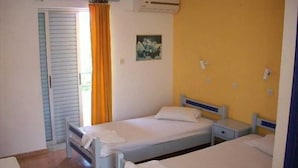 Habitació amb dos llits individuals, una petita taula de nit, un aparell d'aire condicionat i una finestra amb cortines.
