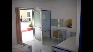 Habitació petita i poc moblada, amb una porta que dóna a zona exterior.