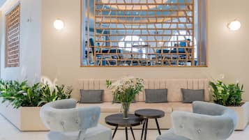 Ein modernes Interieur mit einer Sofagarnitur, zwei Sesseln, einem Couchtisch und einer dekorativen Wandverkleidung.