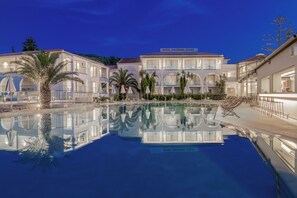 A hotel with a swimming pool, multiple balconies, and palm trees. - Katerina Palace Hotel (Zakynthos)