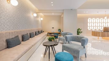 Ein modernes Interieur mit einer Couch, Sesseln, einem Couchtisch und einer Wanddekoration.