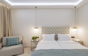 Et moderne hotelværelse med en stor seng, en sofa, et lille sofabord med en plante og et sengebord med en telefon.