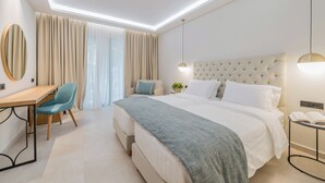 Una habitación de hotel moderna con una cama grande, un escritorio, una silla y una mesita de noche con lámpara.