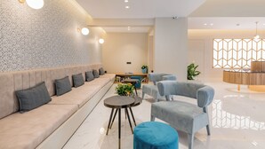 Een modern interieur met een bank, stoelen, een bijzettafeltje en een decoratieve wand.