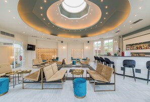 A modern lounge area with sofas, tables, and a bar.