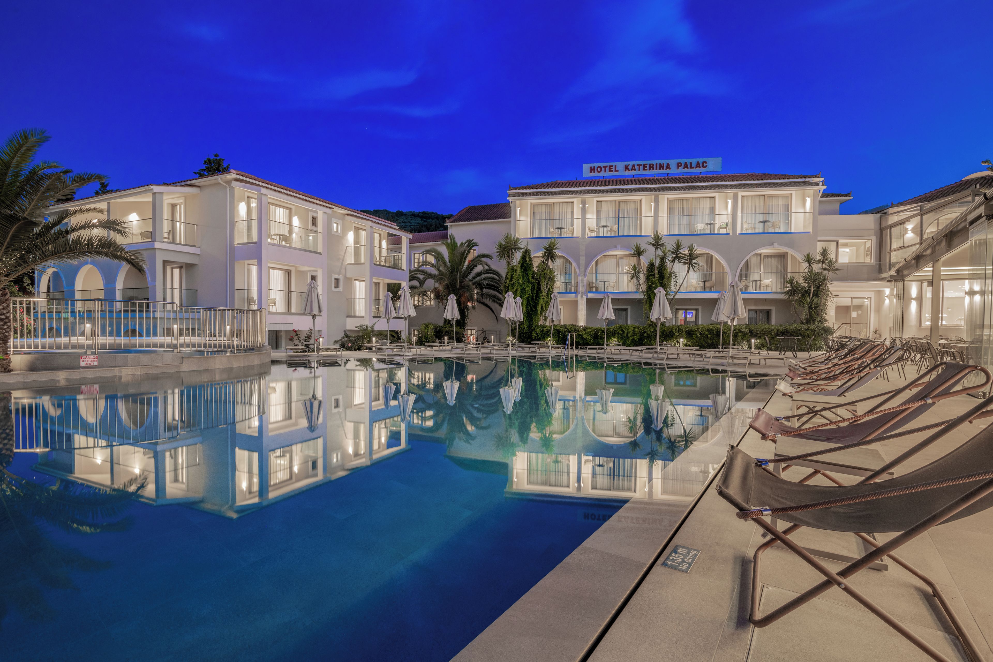 A hotel with a swimming pool, multiple balconies, and a clear sky.