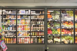 Secciones de bebidas y frutas y verduras refrigeradas en un supermercado.