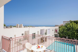 A balcony with a pool, white walls, and air conditioning units. - Tarra Seaside Hotel (Apokoronas)