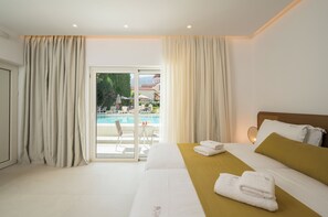 A hotel room with a bed, a view of a pool, and a balcony. - Tarra Seaside Hotel (Apokoronas)