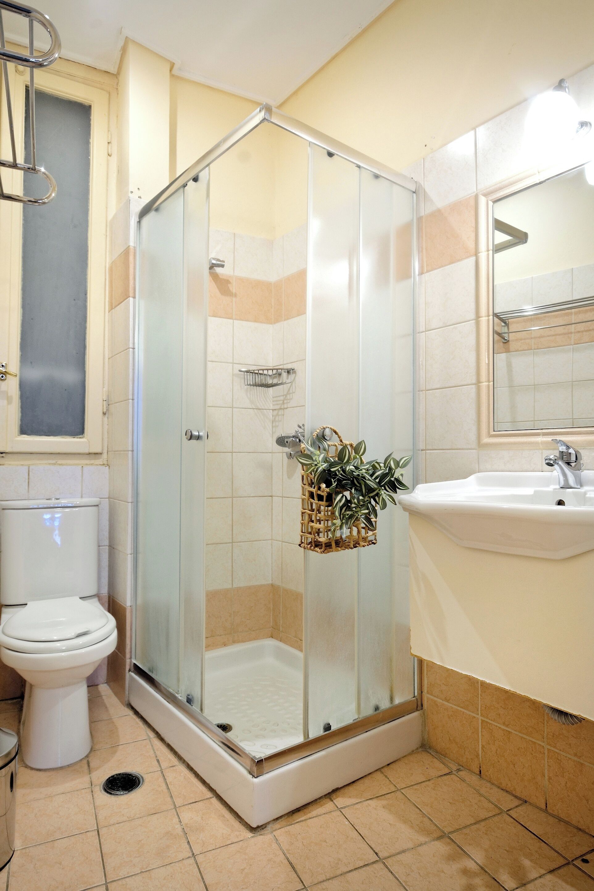 A bathroom with a glass-enclosed shower, a toilet, and a sink.