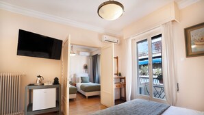 A hotel room with a bed, a desk, a radiator, a TV, and a balcony with a view. - Art Gallery Hotel (Athens)