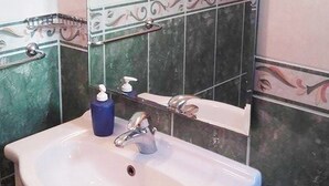 Une salle de bain avec un lavabo blanc, un miroir et un distributeur de savon.