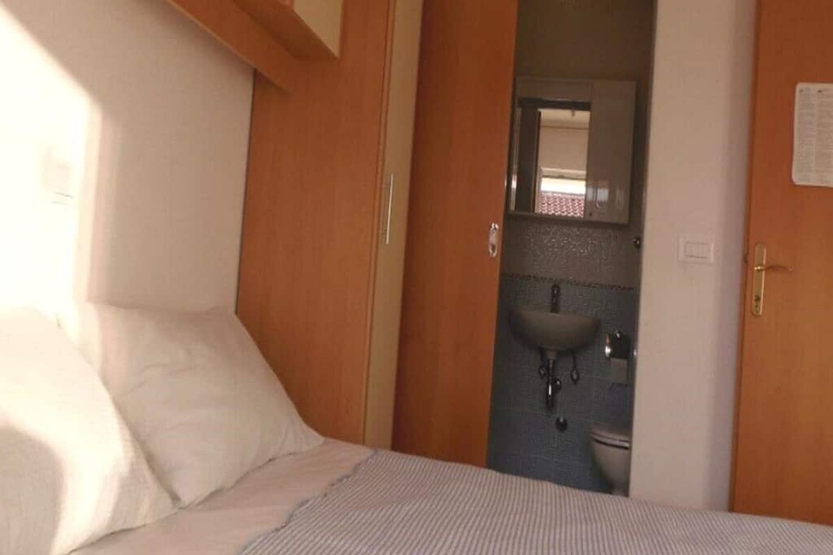Une chambre à coucher avec un lit, une porte en bois et une salle de bain équipée d’un lavabo et d’un miroir.
