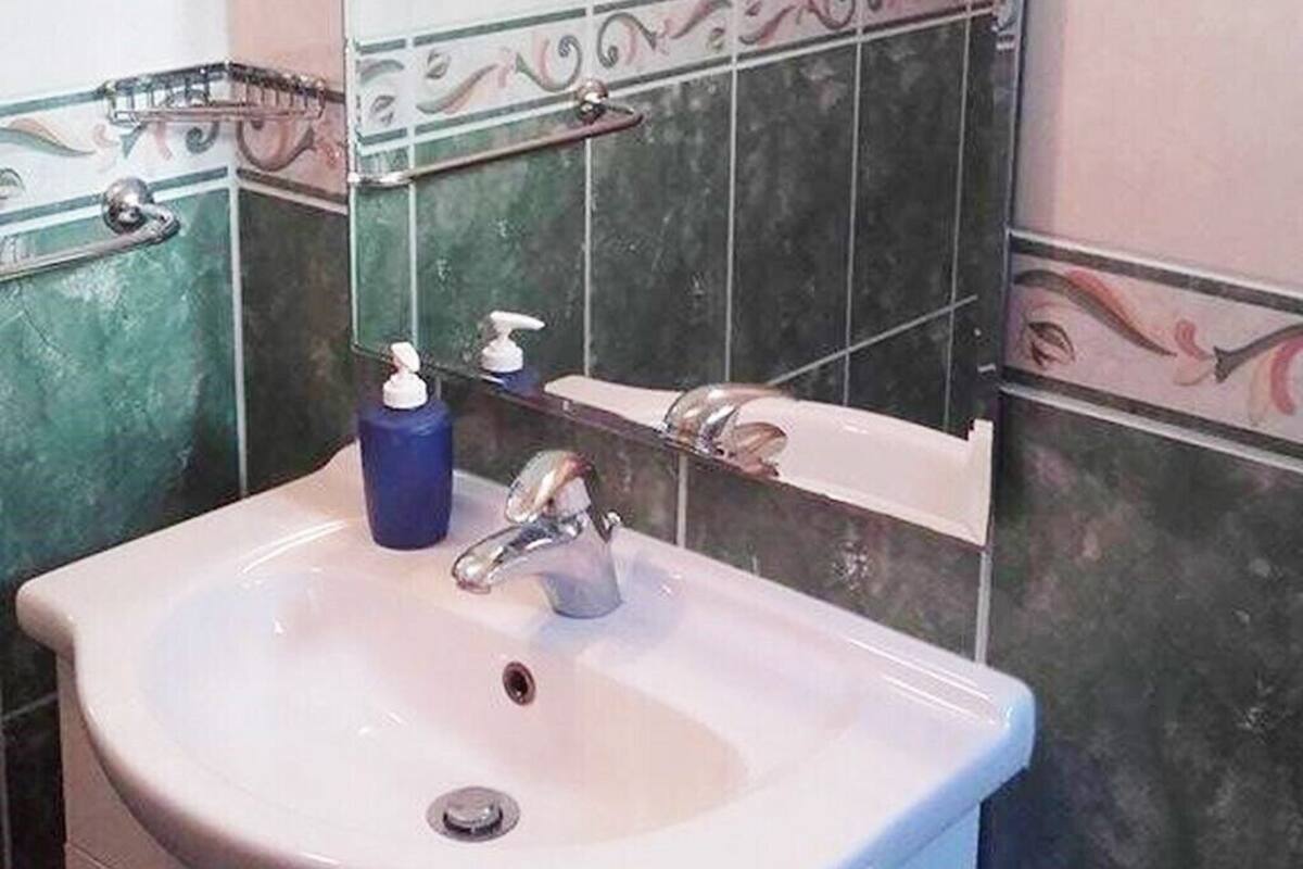 Une salle de bain avec un lavabo blanc, un miroir et un distributeur de savon.