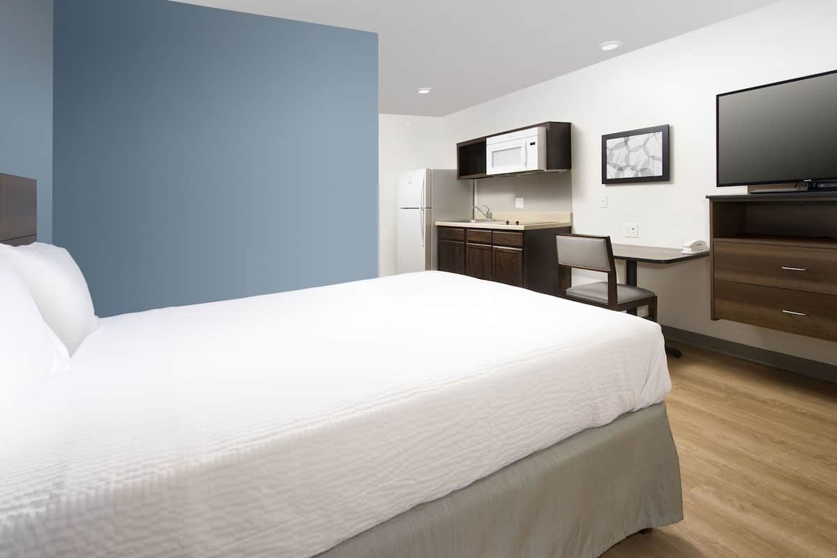 Ein Hotelzimmer mit einem großen Bett, einem Schreibtisch mit Computer, einer Mikrowelle und einem Fernseher.