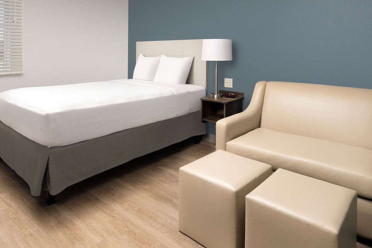 Ein Hotelzimmer mit einem Bett, einem Nachttisch mit Lampe und einem Sofa.