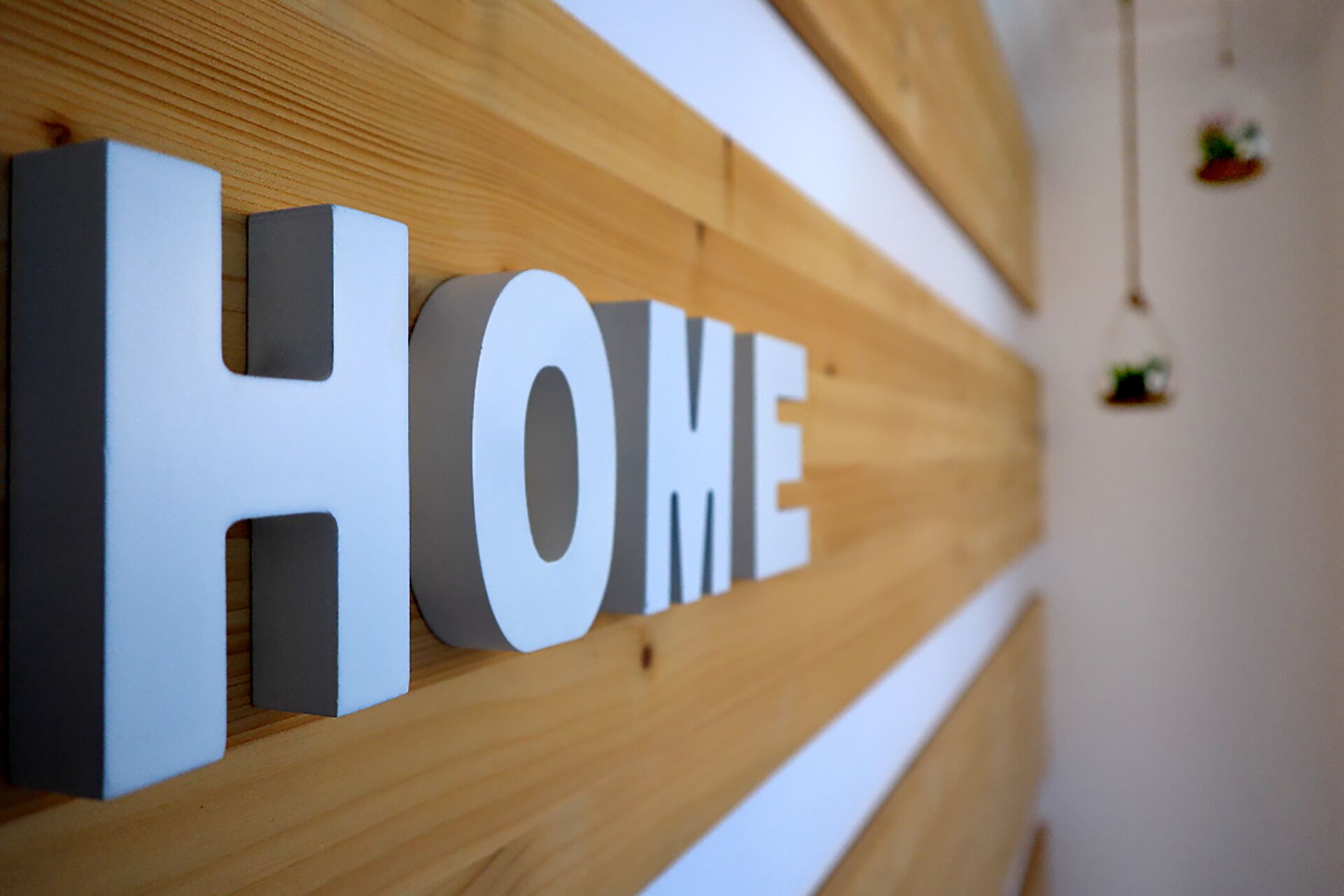 Pared de madera con la palabra “HOME” en letras blancas grandes.