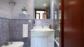 Une salle de bain avec un lavabo blanc, des toilettes et un miroir au-dessus du lavabo.