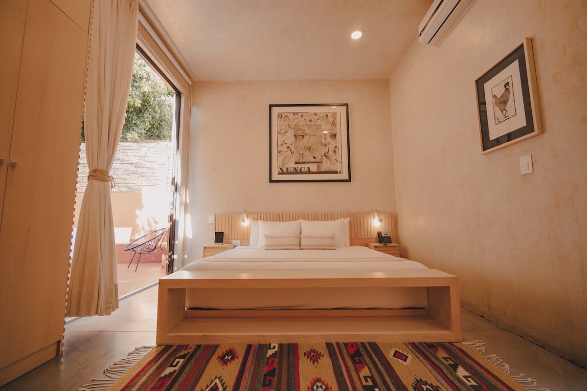 Une chambre à coucher avec un grand lit, un tableau encadré au mur et une fenêtre avec des rideaux.