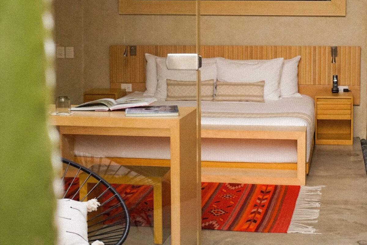 Une chambre à coucher moderne, avec un lit, des tables de chevet, une chaise et un grand tableau encadré au mur.