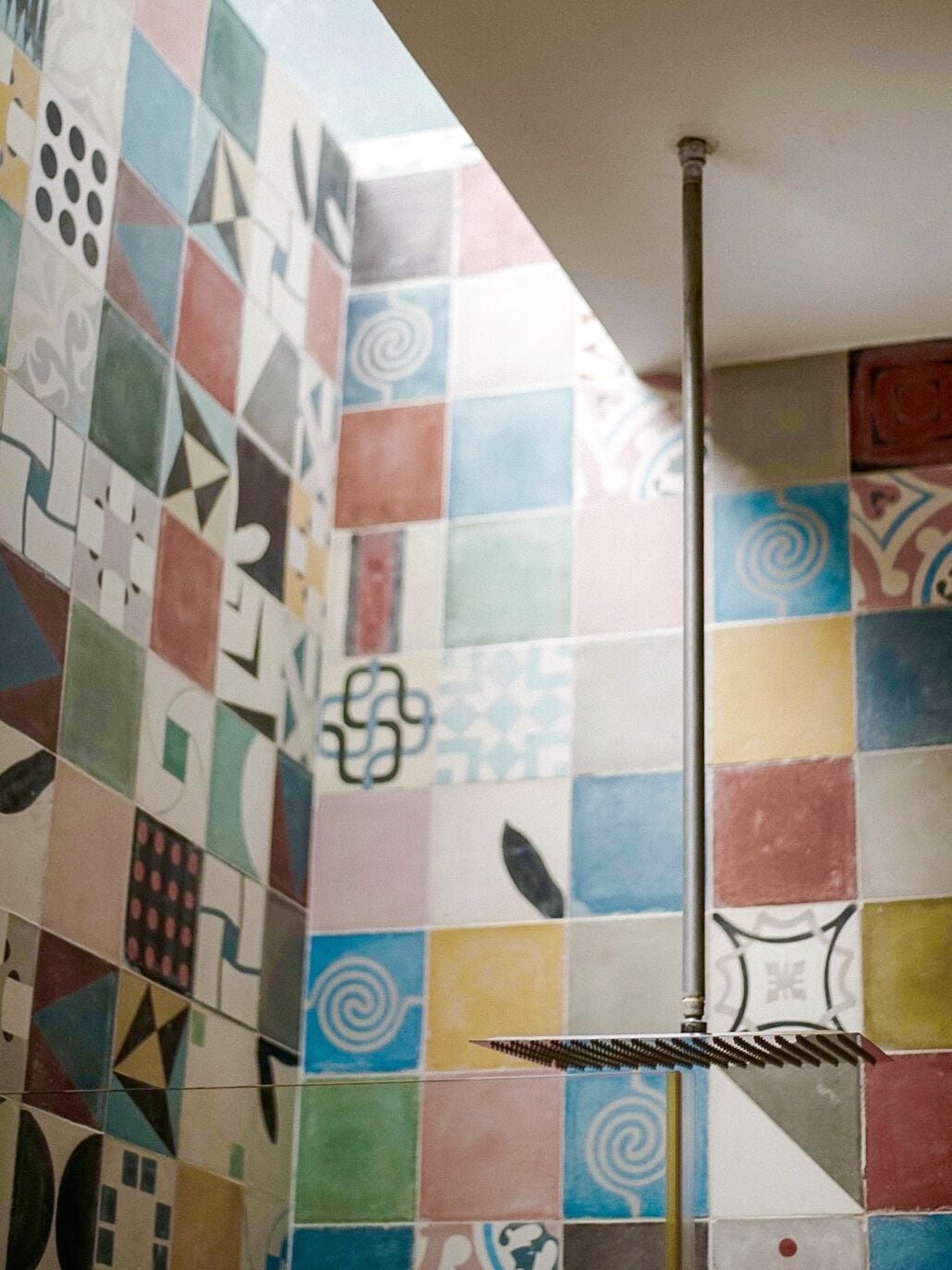 Un baño con azulejos geométricos de colores en las paredes y un toallero de metal.